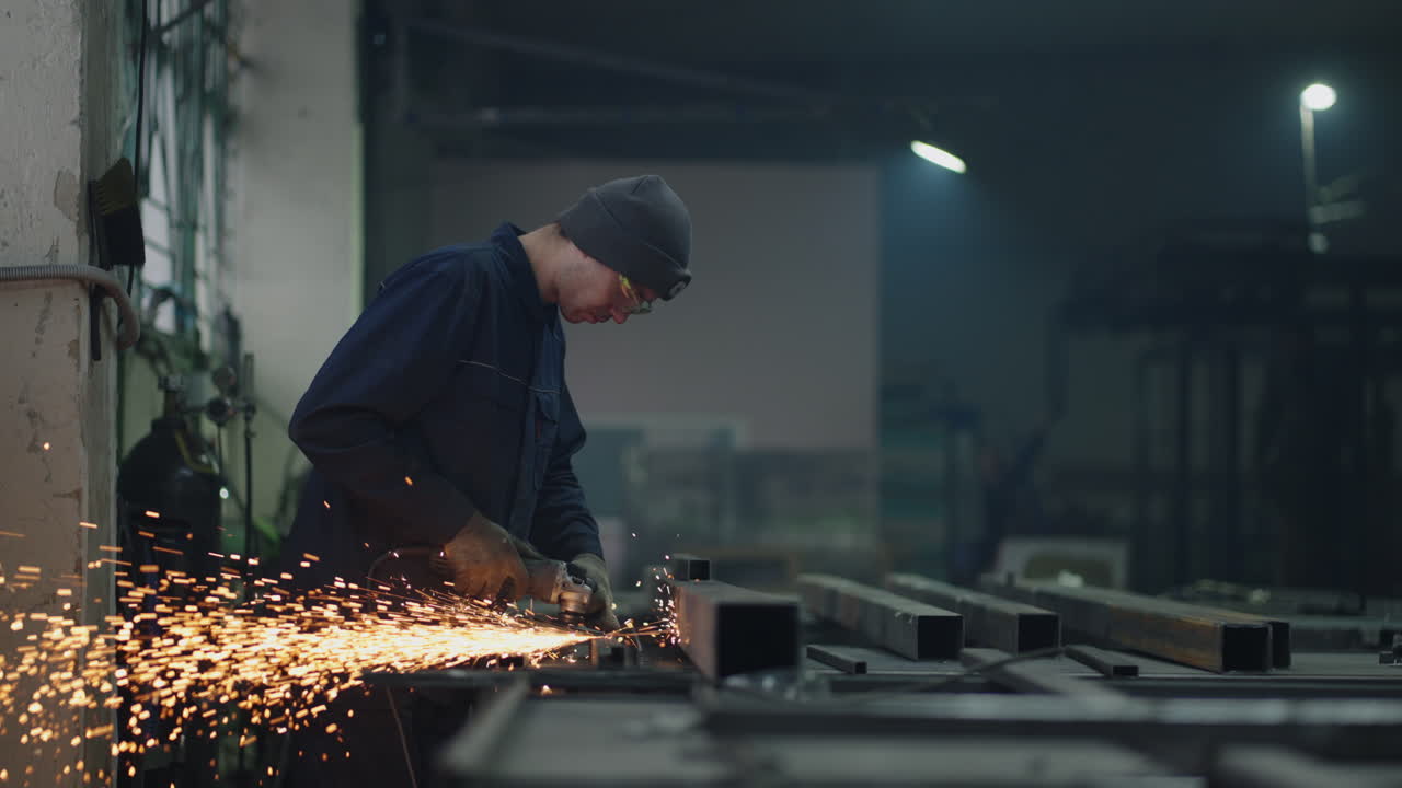 Inquadratura generale: Un uomo con occhiali protettivi lavora con la molatura, lucidatura e sverniciatura di strutture metalliche in acciaio.