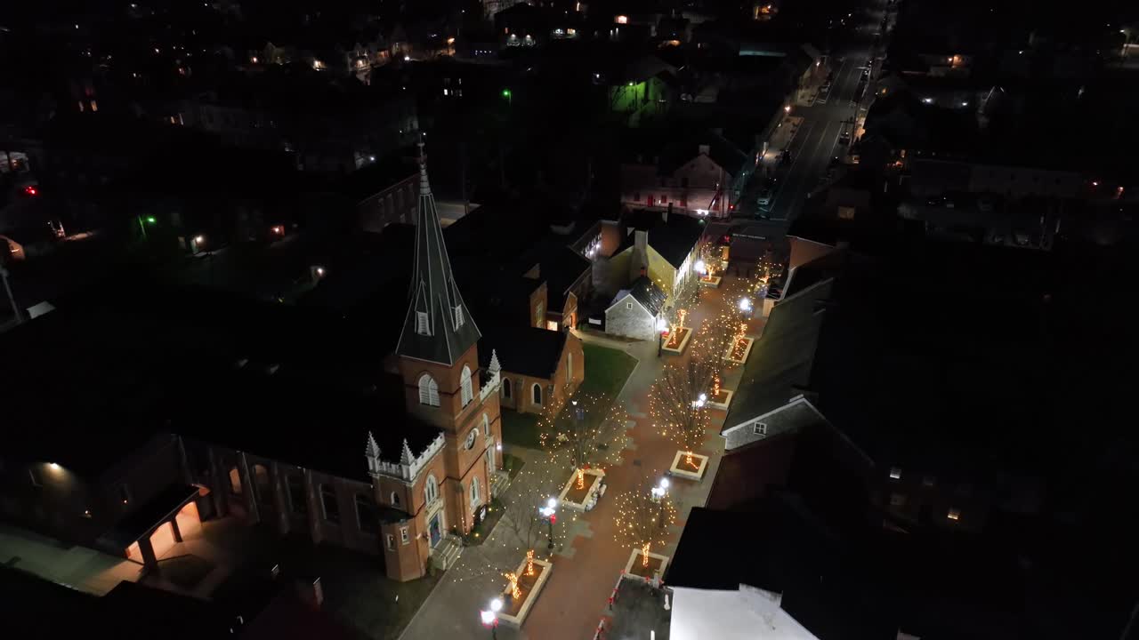 아메리칸 타운의 주요 쇼핑 스트리트와 광장, 밤의 조명, 미국의 역사적인 도시 중심의 크리스마스 장식, 빨간 벽돌 교회 타워 건물, 공중  다운.