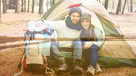 camping couple sitting in tent with backpack over scenic landscape