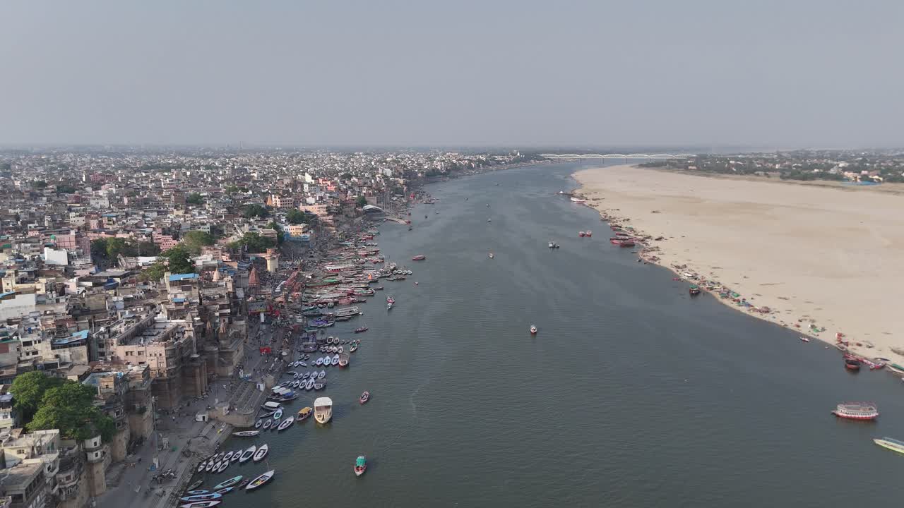 Aerial capture of the sun setting over Varanasi, casting a golden glow over the city's tightly packed neighborhoods and historic temples.