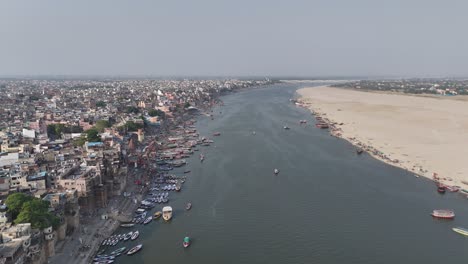 aerial capture of the sun setting over varanasi, casting a golden glow over the city's tightly packed neighborhoods and historic temples.