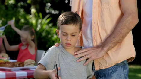 retrato de un padre vigilando a su hijo preparando una barbacoa