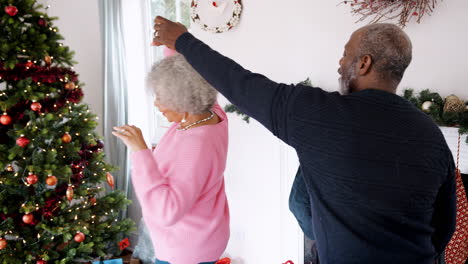 Senior-black-couple-dancing-in-their-living-room,-decorated-for-Christmas,-handheld