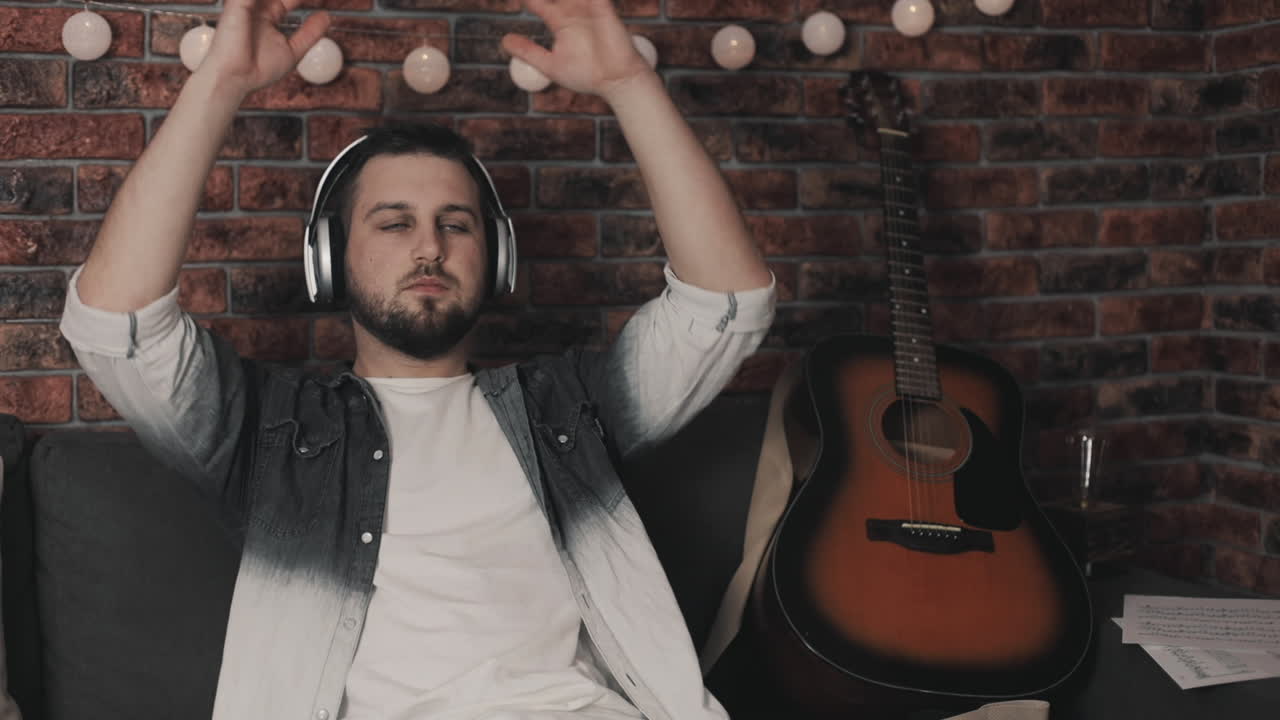 집에서 무선 헤드폰으로 음악을 듣는 젊은 음악가