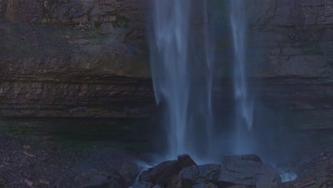 una serena cascada cae sobre un acantilado rocoso en un entorno natural tranquilo
