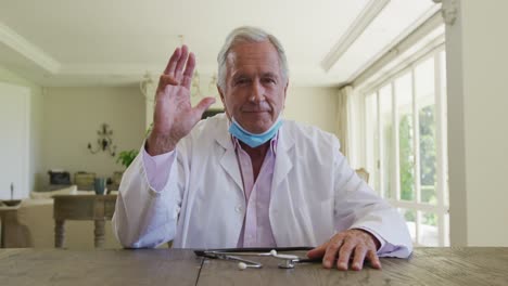 Portrait-of-caucasian-senior-male-doctor-with-lowered-face-mask-talking-looking-at-the-camera