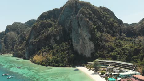 towering limestone cliff restraining tonsai bay in ko phi phi don island, thailand - aerial fly-over shot