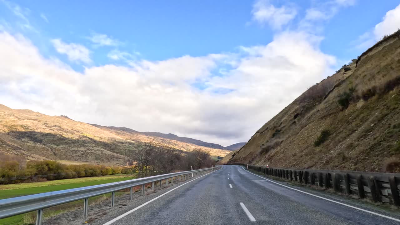 A picturesque journey through New Zealand's mountainous landscapes, showcasing vibrant autumn foliage and expansive skies under natural lighting