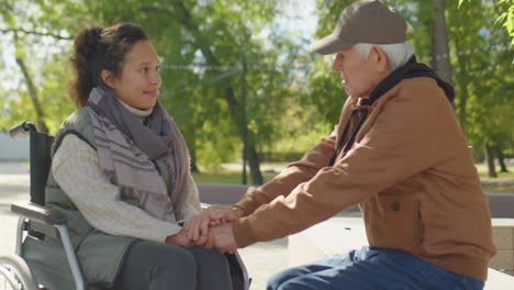 senior man talking with woman in wheelchair in park