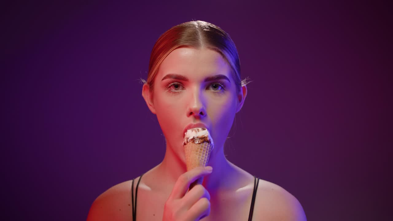 Mujer caucásica con fondo de estudio comiendo un helado, toma de primer plano