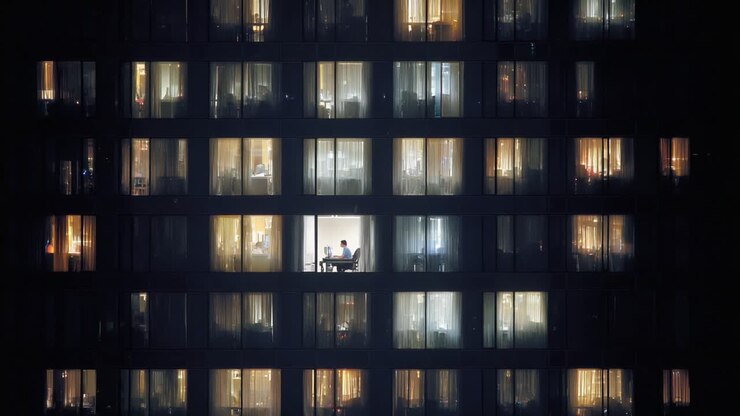 Conversazioni intime serali: uno sguardo su due persone che condividono momenti a un tavolo in un moderno appartamento di un grattacielo, circondati da luci calde interne e ambienti esterni oscurati