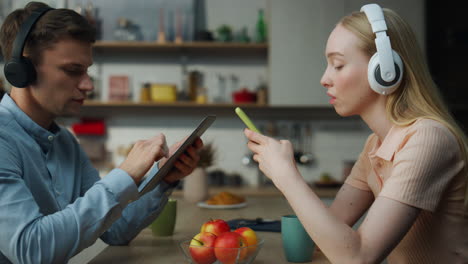 Couple-ignoring-communication-addicted-to-gadgets-close-up.-Pair-listening-music