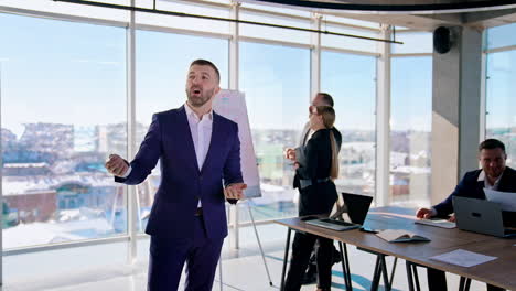 portrait of a businessman talking on camera. confident entrepreneur in blue costume speaking about his success in the light office with business people working.