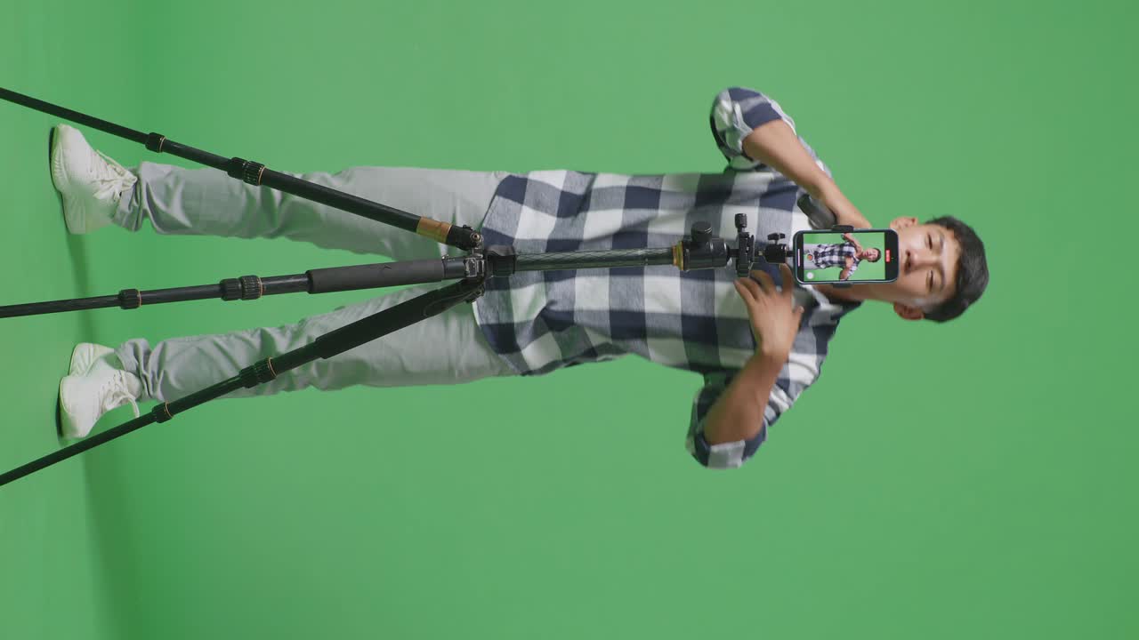 스마트폰 기록으로 가득 찬 신체 젊은 아시아 십대 소년 마이크를 들고 녹색 화면 배경에