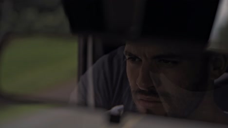 a close-up from the rearview mirror captures a man driving through costa rica, with a blurred green landscape outside, filmed during a scenic journey