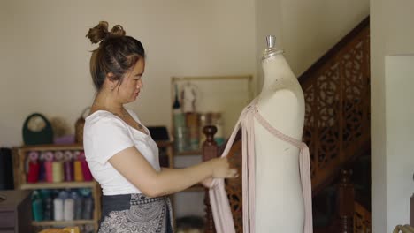 woman braiding fabric onto a dress form in a workshop