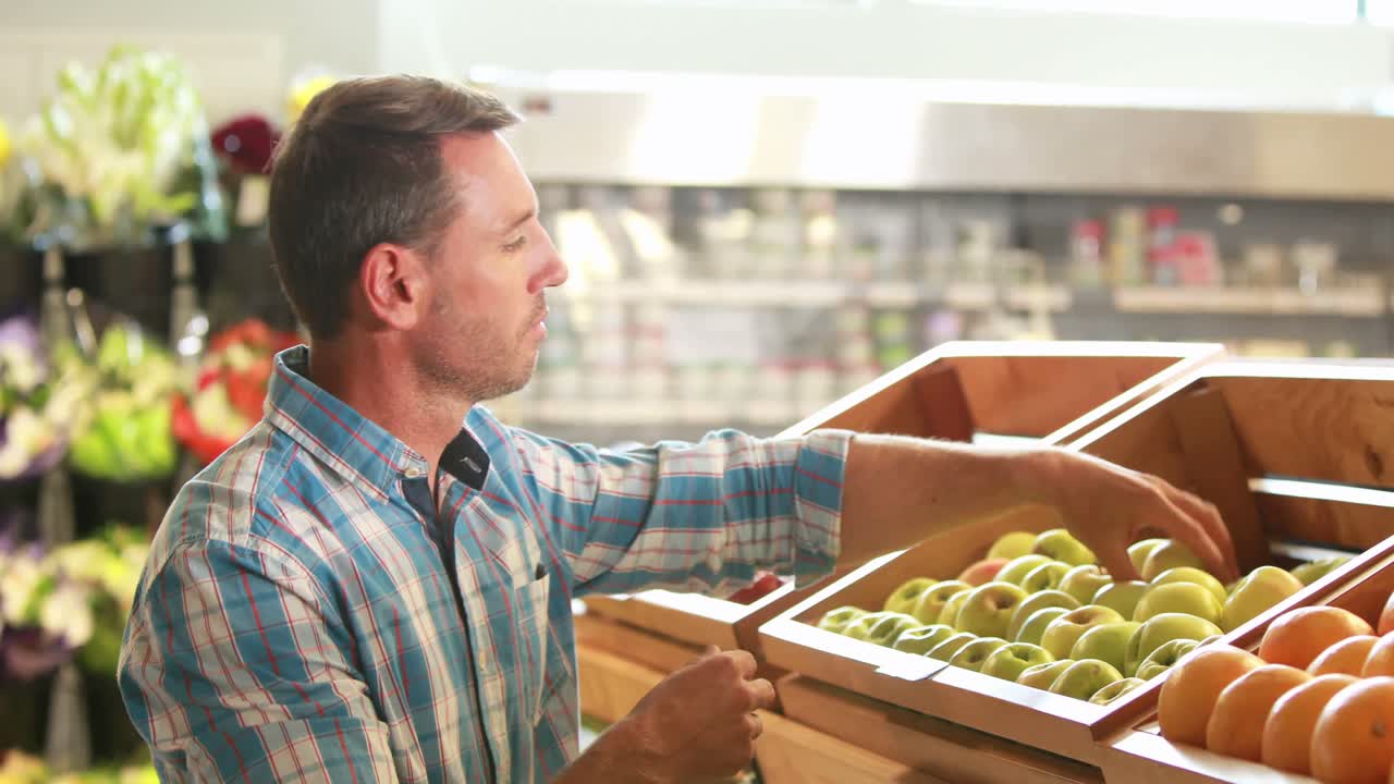 hombre recogiendo frutas en el supermercado