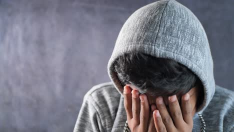 hombre triste con capucha cubre la cara con las manos aisladas en negro