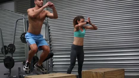 fit couple doing set of box jumps