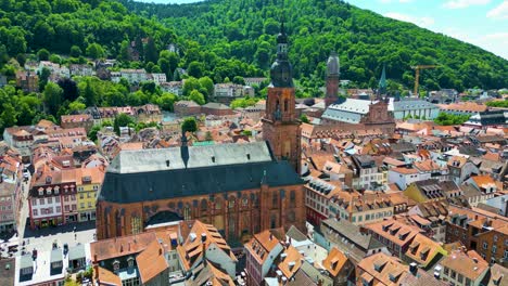 4k aerial drone video of the historic heiliggeistkirche and jesuitenkirche churches along the neckar river in heidelberg, germany