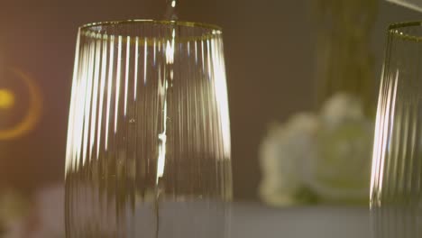 primer plano de una persona vertiendo champán en un vaso en la mesa preparada para la comida en la recepción de la boda 4