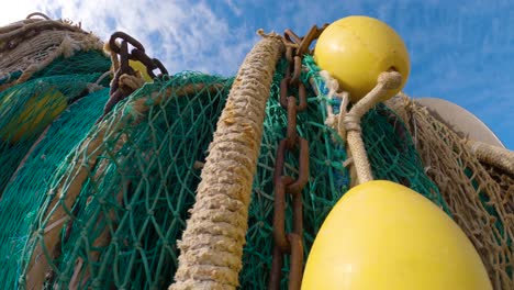 Close-up-of-green-fishing-net-with-chains-and-yellow-buoys