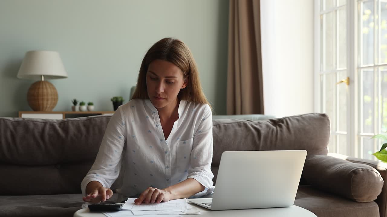 нервная запутанная молодая женщина рассчитывает платежи по счетам с трудностями