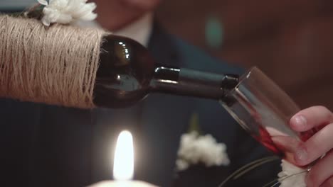 young man pours wine into a glass at dinner time close-up slow motion