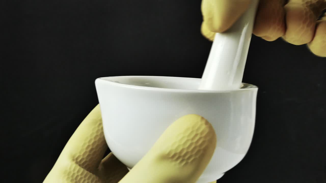 руки в перчатках работают точно с фарфоровым раствором, демонстрируя составление фармацевтических формул в контролируемой лабораторной обстановке. сцена подчеркивает научную строгость.