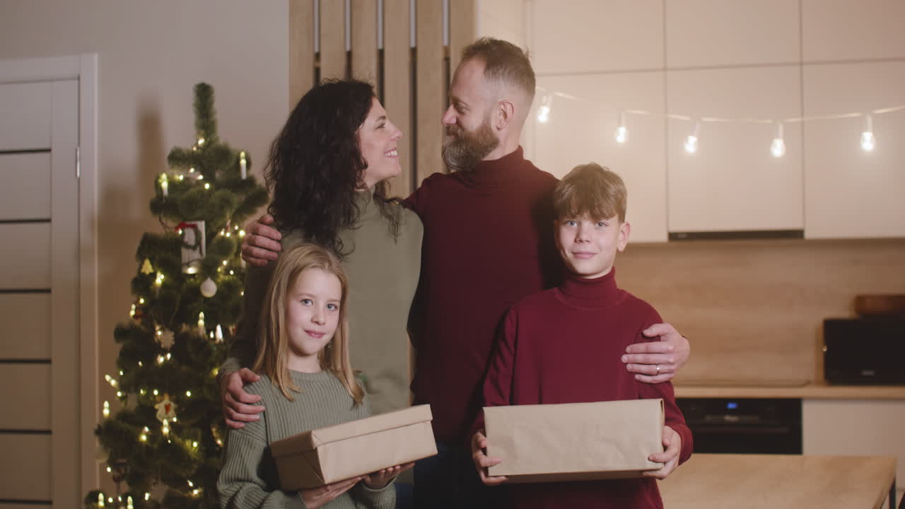 Front View Of A Family Smiling At Camera In A Room Decorated With A Christmas Tree