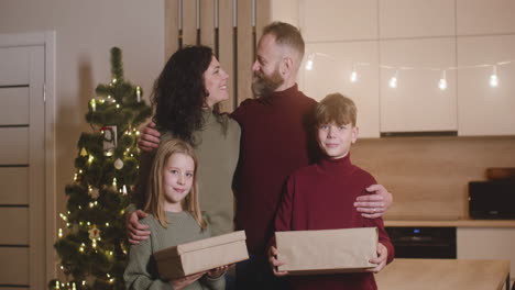 front view of a family smiling at camera in a room decorated with a christmas tree