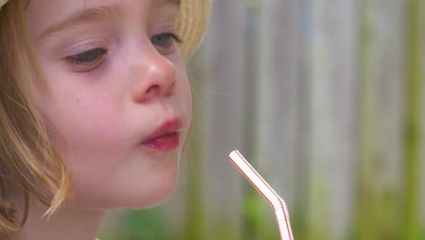 a happy little girl takes a sip of her drink and then smiles at the camera