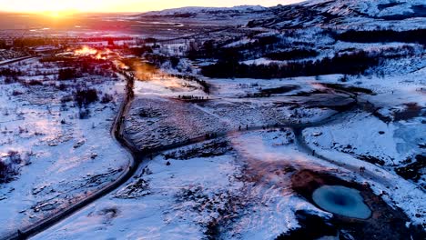 panoramic view with a drone of mountains under the red sunset in geysir, iceland. there is geysers in the wonderful famous place for travelers. a lot of smoke is getting out of the geyser.