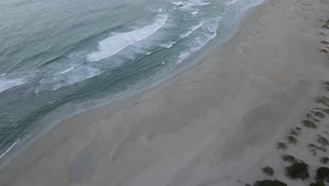 Drone-aerial-over-a-quiet-pristine-beach-during-sunrise