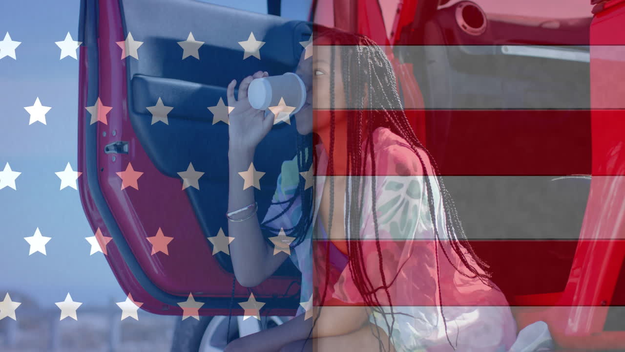 animación de la bandera de los ee.uu. sobre feliz mujer afroamericana en el coche bebiendo café en el coche por la playa