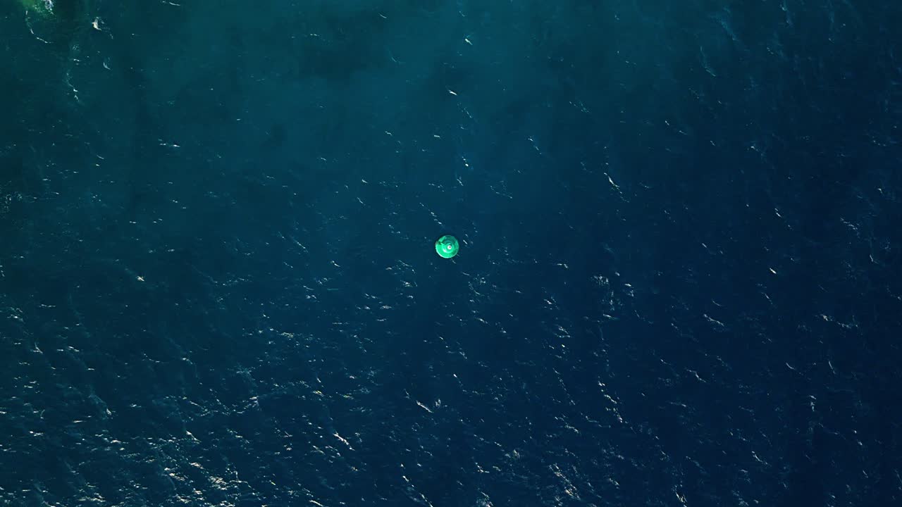 Aerial drone top down of buoy in open green blue gradient ocean water