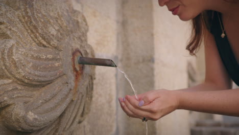 Mädchen-Nähert-Sich-Einem-Städtischen-Brunnen-Und-Trinkt-Wasser-In-Zeitlupe,-Mittlere-Nahaufnahme