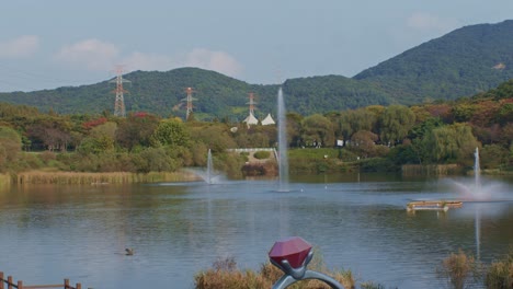 a beautiful picturesque panoramic wide angle view of the lake and park next to the mountains with fountains and water at daytime sunlight