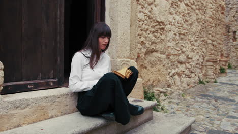 religious young woman reading the bible book at the entrance of the church