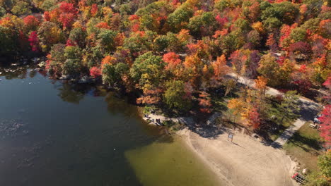 Toma-Aérea-De-Drones-Volando-Sobre-Un-área-De-Campamento-Rodeada-De-Coloridos-árboles-De-Otoño-Junto-Al-Lago-Reflejado-Y-Personas-De-Pie-Y-Observando-La-Belleza,-Canadá,-10-De-Octubre-De-2022