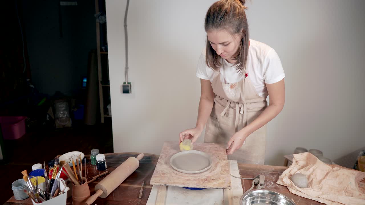 한 여성 이 미술 스튜디오 에서 도자기 접시 를 만들고 있다