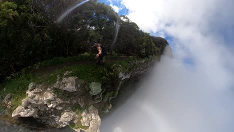 a young and strong solo hiker is running along the steep edge of espigao amorelo in madeira with thin clouds around him during a sunny day with clear blue sky.