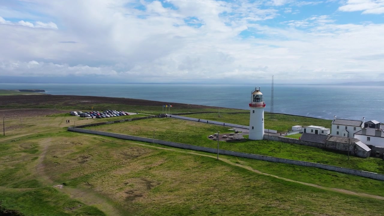 Loop Heads fyrtårn omgivet af åbne marker og Atlanterhavet. Velegnet til rejseindhold eller dokumentarer.