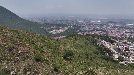 Aerial-view-rising-over-hills,-revealing-the-Ecatepec-de-Morelos-town,-in-Mexico
