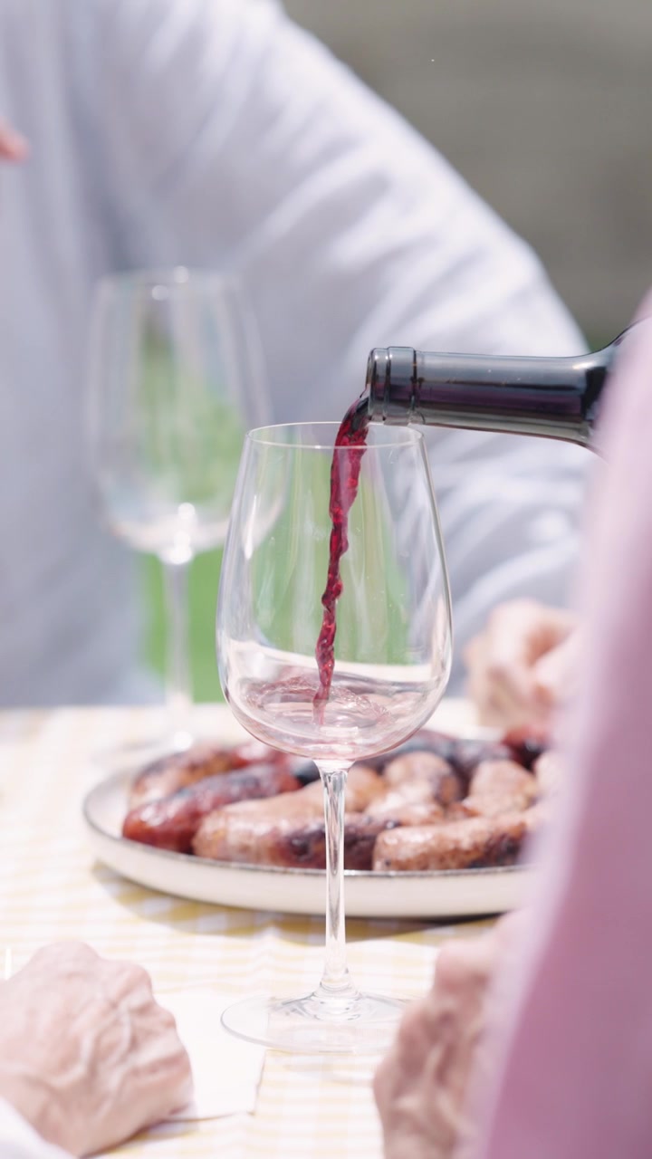 Versare vino rosso nei bicchieri a una cena all'aperto