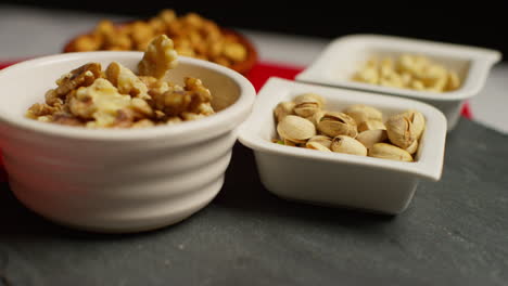 fotografía de cerca de cuencos que contienen anacardos tostados secos cacahuetes pistachos nueces y avellanas girando 1