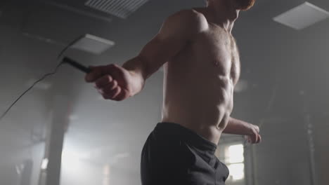 a young athletic man with prominent muscles jumps on a rope in the gym in slow motion