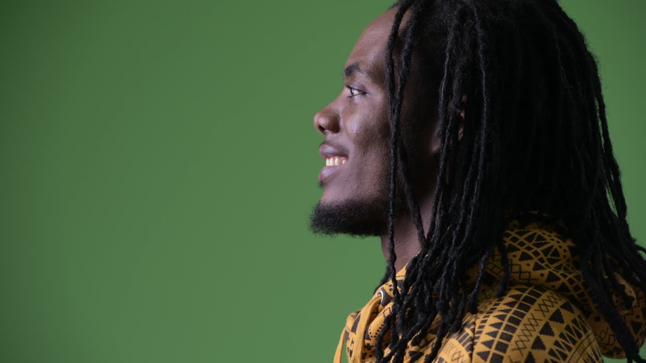 joven hombre africano guapo con dreadlocks contra un fondo verde