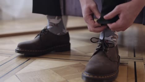 Close-up-hands-of-man-groom-adjusting,-wearing,-putting-his-wedding-shoes-in-hotel-room-near-window