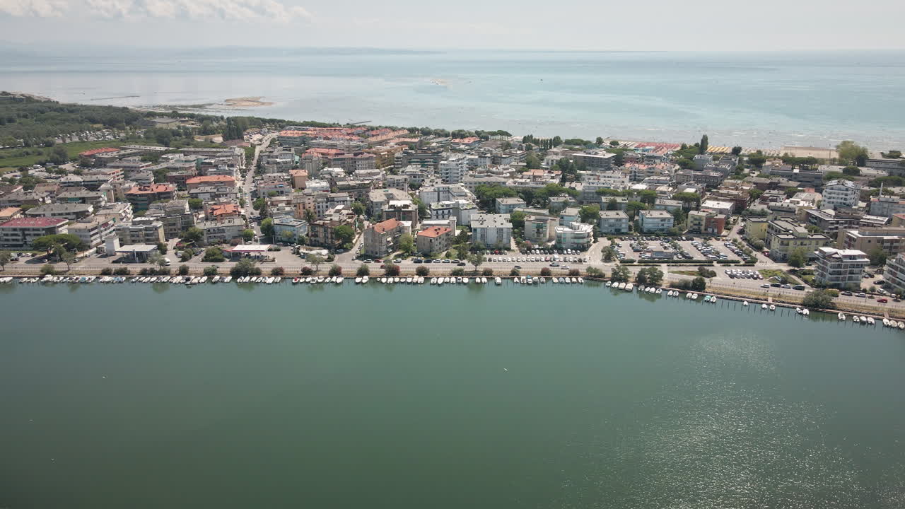 Sujuva 4K UHD -dronekuvaus oikealta vasemmalle Grado-kaupungin yllä esitellen asuinrakennuksia, venesatamaa ja laajaa laguunia – täydellinen matkapromoihin, B-rullaan ja kaupunkimaisemiin.